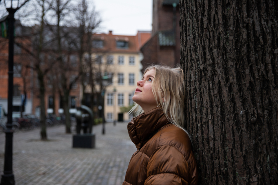 Une adolescente qui réfléchit contre un arbre